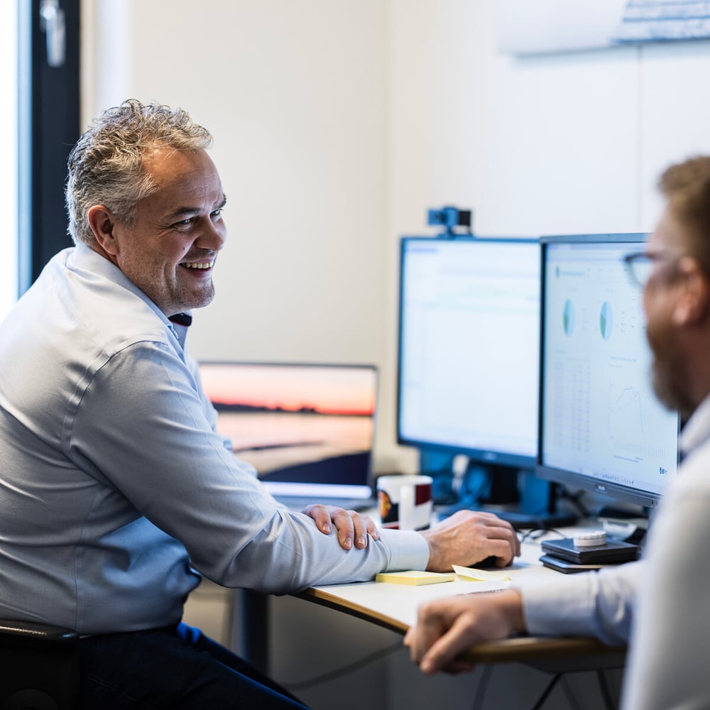 To personer jobbende foran PC-skjermer